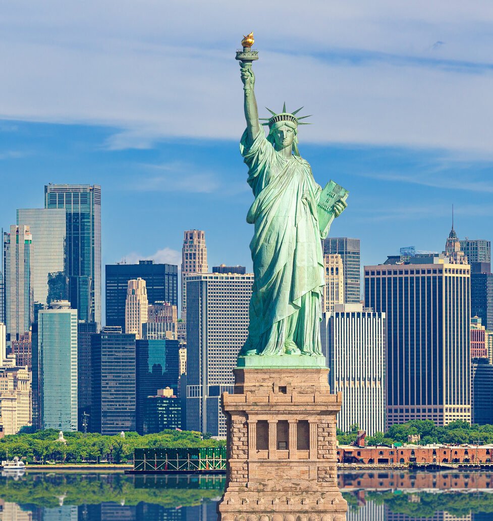 statue of liberty and new york city skyline with manhattan financial district, world trade center, empire state building and blue sky.